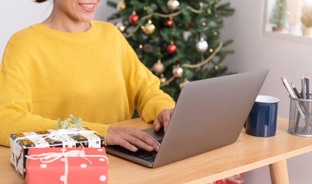 business woman working on computer in Christmas day with gift box and christmas tree background.