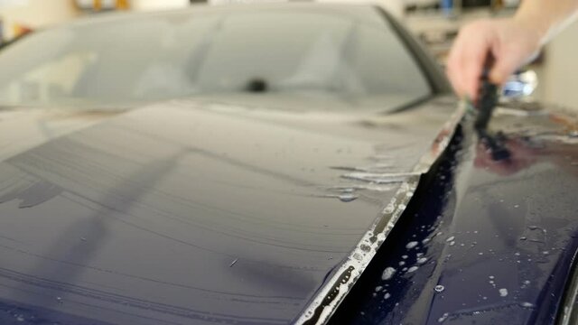 Close up to PPF installation process on a front headlight and hood. PPF is a Paint Protection Film which protect paint from scratches and stone chips. Concept of: Guard, Protect, Car, New, Work.