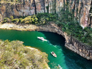 Canyon view from top, green water and three boats, high rock cliffs, sunny day in Capitolio MG Brasil -  Lago de Furnas