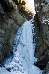 Fototapeta na wymiar Frozen waterfall with huge beautiful icicles hanging from the rocks. Chegem