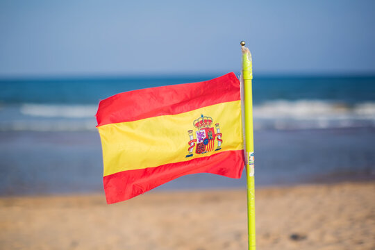 Spanish flag waving on the beach in front of the sea