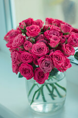 A chic bouquet of small pink roses in a jar on the windowsill. Cute still life 