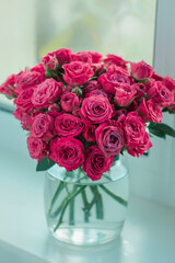 A chic bouquet of small pink roses in a jar on the windowsill. Cute still life 