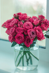 A chic bouquet of small pink roses in a jar on the windowsill. Cute still life 