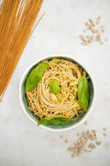 spaghetti with pesto sauce in a handmade pottery bowl on a marble surface dish cuisine plated delicious dish vegan meal vegan recipe wholegrain pasta and sunflower seeds