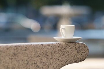 White porcelain coffee cup on bench handle in sunny park, selective focus