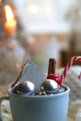Mug filled with various Christmas decorations, soft blanket and lit candles. Hygge at home. Selective focus.
