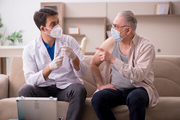 Young male doctor visiting old patient in vaccination concept