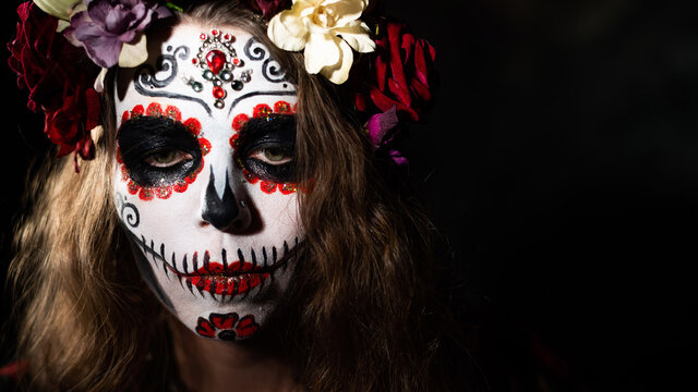 Woman in santa muerte makeup on a black background. Girl wearing traditional mexican holy death costume for halloween. Copy space