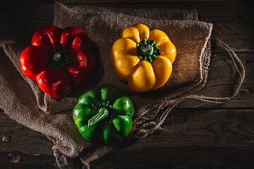 Peppers of different colors on sackcloth on a rustic wooden table. overhead view.