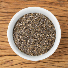 Chia seeds in a white bowl over wooden table