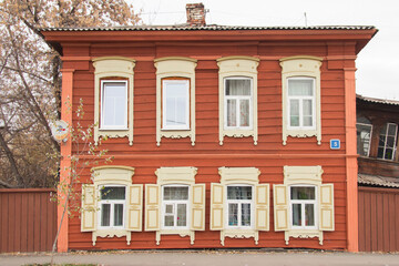Fototapeta premium Wooden architecture of Siberia, old Windows with wooden carved architraves. old peeling paint on the wooden Windows