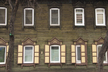 Wooden architecture of Siberia, old Windows with wooden carved architraves. old peeling paint on the wooden Windows