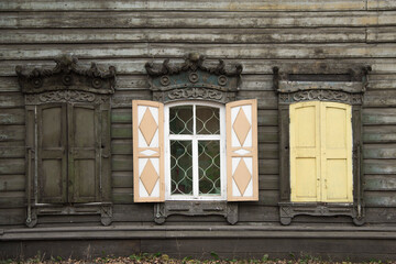 Wooden architecture of Siberia, old Windows with wooden carved architraves. old peeling paint on the wooden Windows