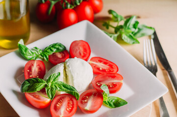 Caprese salad with mozarella cheese,tomatoes and basil on a white plate