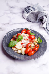 Gnocchi with tomatoes, red sauce, cheese and basil leaves