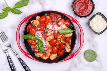 Gnocchi with tomatoes, red sauce, cheese and basil leaves