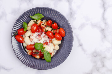 Gnocchi with tomatoes, red sauce, cheese and basil leaves