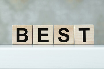 Wooden cubes with letters on the table in the office. Text BEST. Financial concept.