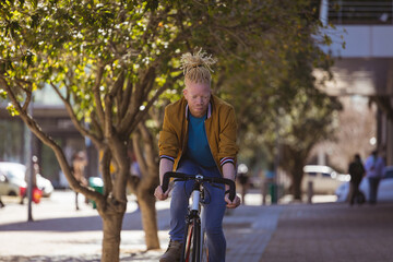 Thoughtful albino african american man with dreadlocks riding bike
