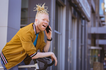 Happy albino african american man with dreadlocks talking on smartphone