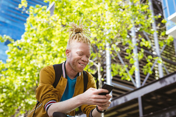 Happy albino african american man with dreadlocks using smartphone