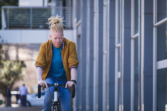 Thoughtful albino african american man with dreadlocks riding bike
