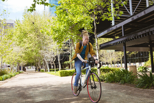 Thoughtful albino african american man with dreadlocks riding bike