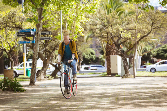 Thoughtful albino african american man with dreadlocks riding bike