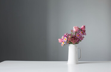 pink flowers in white jug on background gray wall