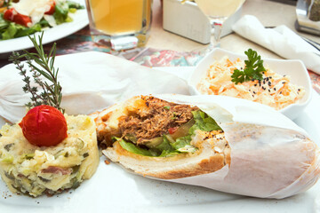 Delicious pulled pork sandwich with potato puree and coleslaw salad