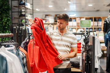 Man choosing hoodie in shop