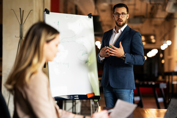 Businessman present his idea to working team. Young happy man presenting businessplan.