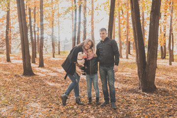 Fototapeta premium Family spend time in autumn park with a dog. Father, mother and daughter and jack russell terrier dog having fun in fall
