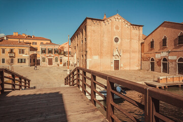 Empty sunny square with brick houses, bridges and watel canals in historical area Cannaregio