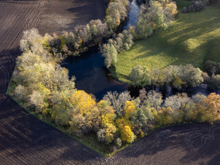 Aerial view of river, agriculture fields and trees. Drone photography taken in Sweden in autumn, October. 