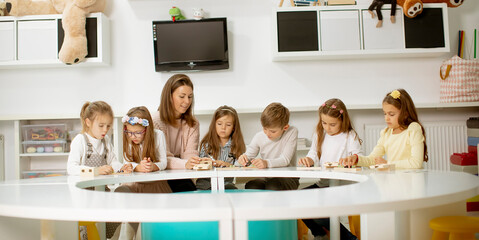 Group of cute little kids playing with preschool educational toys with kindergarden teacher