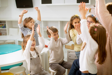 Cute preschool kids put hands together with their nursery teacher