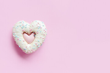 Flat lay of two heart shaped gingerbread cookie with sprinkles and icing on pink background