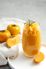 Front view of persimmon in white plate , green leaf , white napkin with grey background for food advertising 
