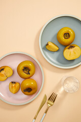 Top view of blue and pink dish of persimmon , pork , knife , water glass in light pink background for food advertising 