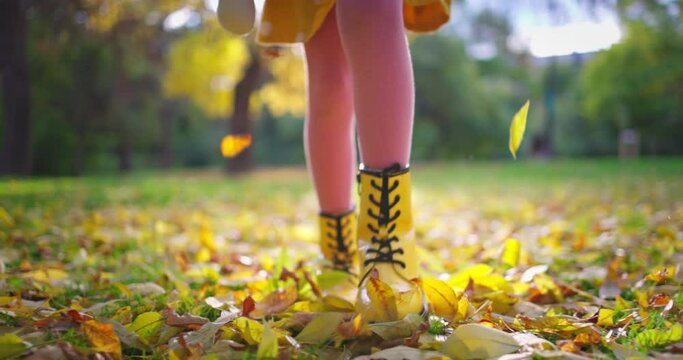 Girl legs walking on fallen leaves in autumn park. Running woman outdoor.