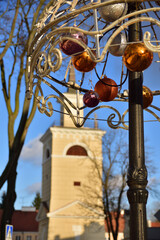 Fototapeta na wymiar Christmas decorations against the background of the historic belfry on a sunny day in an unusual shot. Winter.