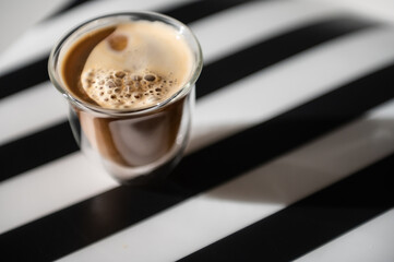 Photo of cup with black coffee and shadow on black and white background
