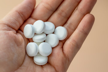 round white tablets poured chaotic light orange background,heart shape.pills in woman hand or green spoon.natural herbs,organic pills,vitamins from medicinal plants,calcium, antidepressants,painkiller