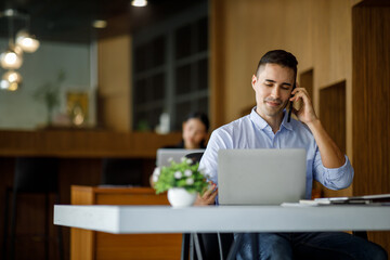 Smiling businessman working on a laptop computer in a modern office,doing finances, accounting analysis, report data pointing graph Freelance education and technology concept.