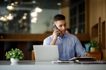 Smiling businessman working on a laptop computer in a modern office,doing finances, accounting analysis, report data pointing graph Freelance education and technology concept.