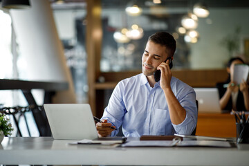 Smiling businessman working on a laptop computer in a modern office,doing finances, accounting analysis, report data pointing graph Freelance education and technology concept.