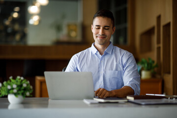 Smiling businessman working on a laptop computer in a modern office,doing finances, accounting analysis, report data pointing graph Freelance education and technology concept.