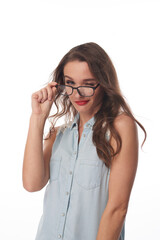 Portrait of confident Caucasian student girl with wavy hair adjusting eyeglasses while winking at camera